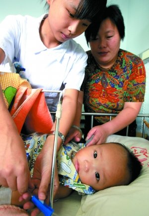2008年9月13日，醫(yī)務(wù)人員為10個(gè)半月大的腎衰竭患兒換藥，該患兒因喝三鹿奶粉而患病。新華社記者 陳飛 攝